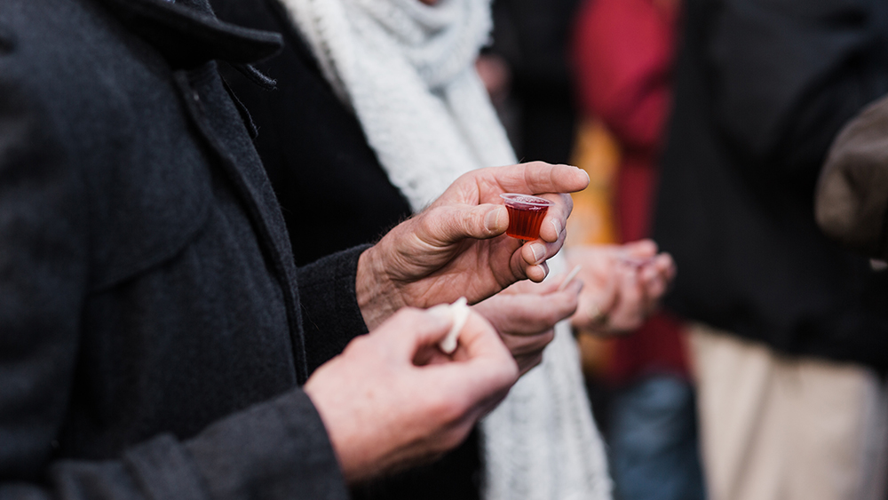 People holding individual communion cups outside