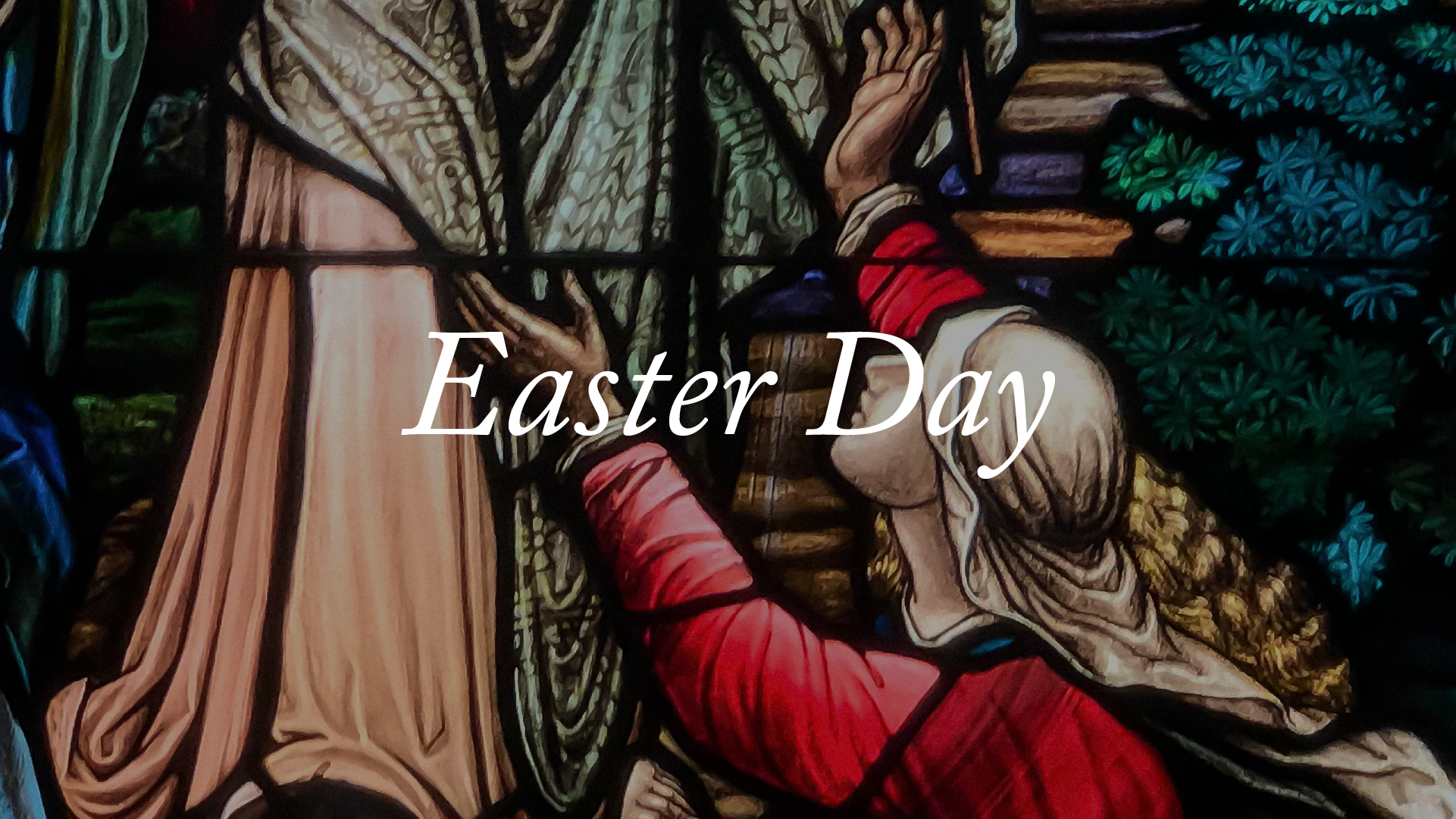 A stained glass window of a woman kneeling with raised hands at Jesus' feet.